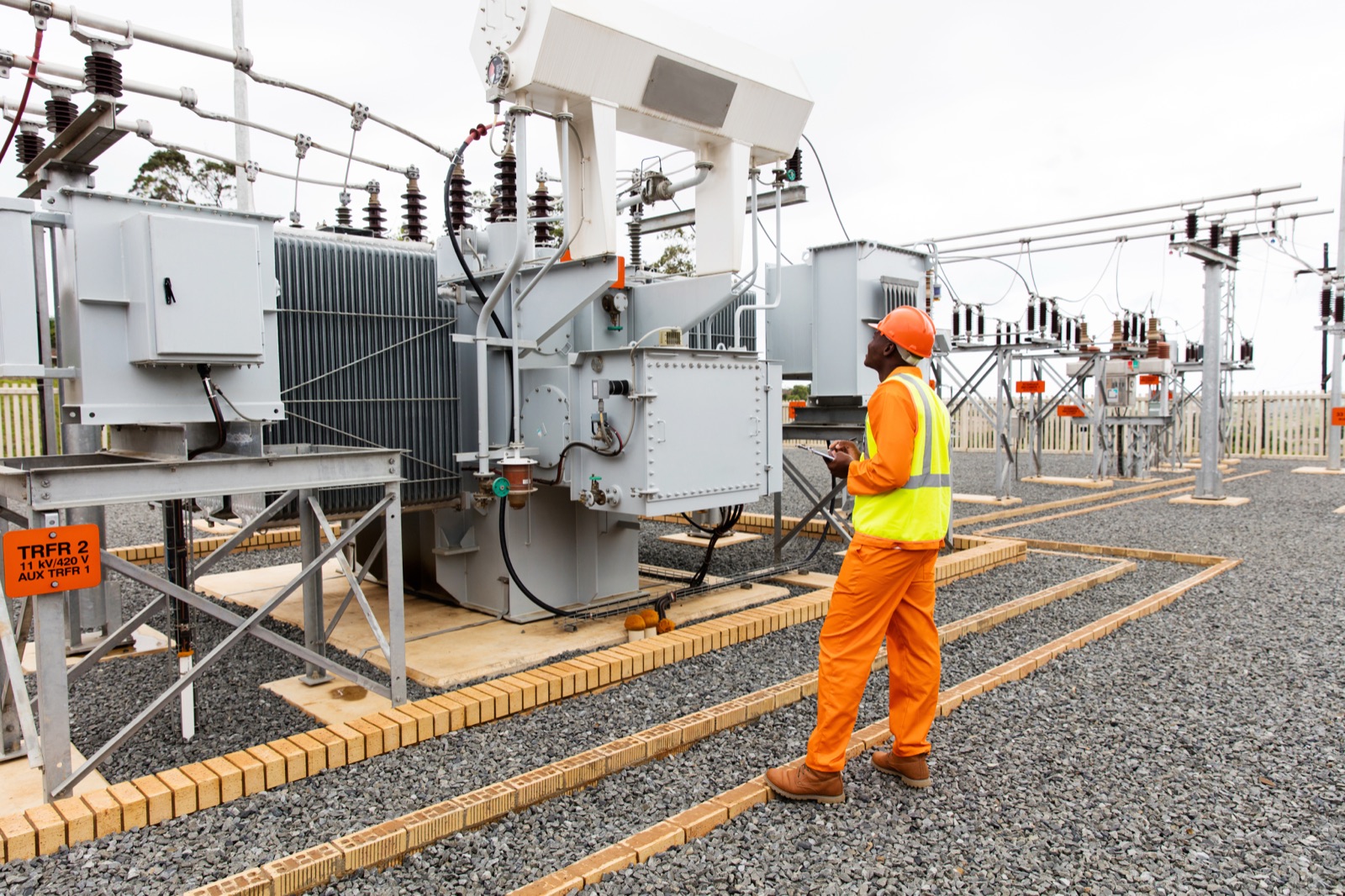 Engineer inspecting a power transformer at an electrical substation
